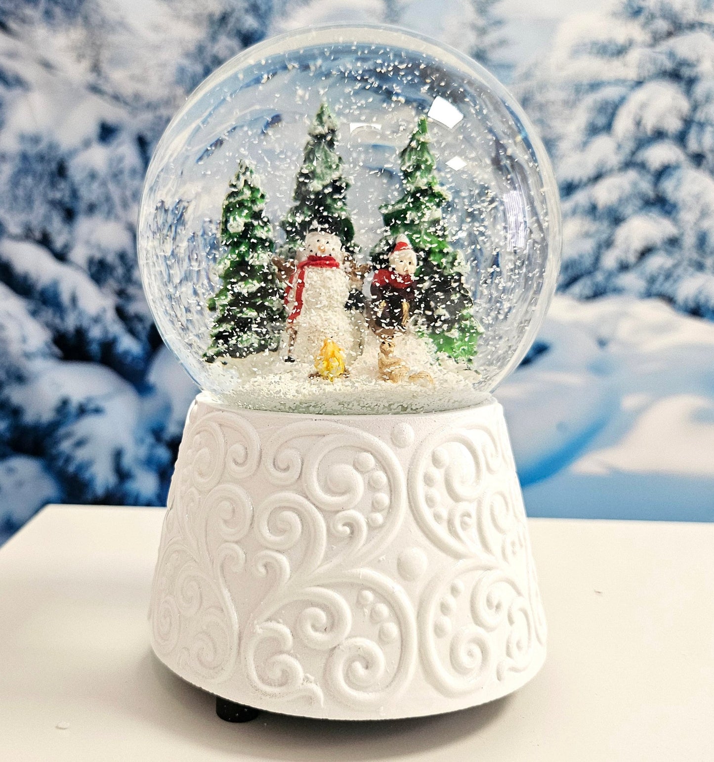 Edle Schneekugel Schneemann vor Lagerfeuer auf weißem Ornamentsockel 100 mm Durchmesser mit Spieluhr - Schneekugelhaus