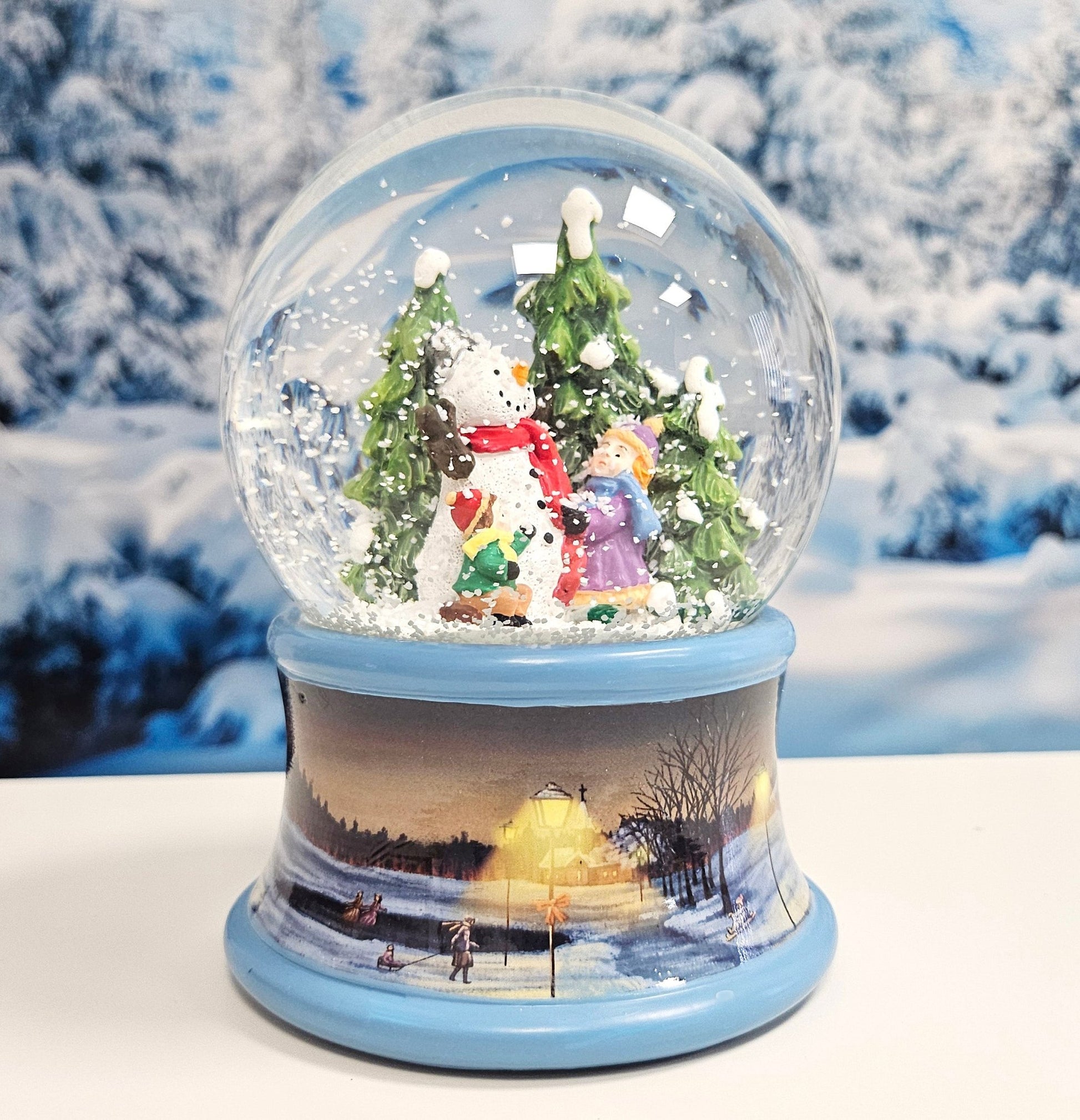 Schneekugel Kinder bauen Schneemann auf Sockel Winterlandschaft Eisläufer blau mit Spieluhr 10 cm Durchmesser - Schneekugelhaus