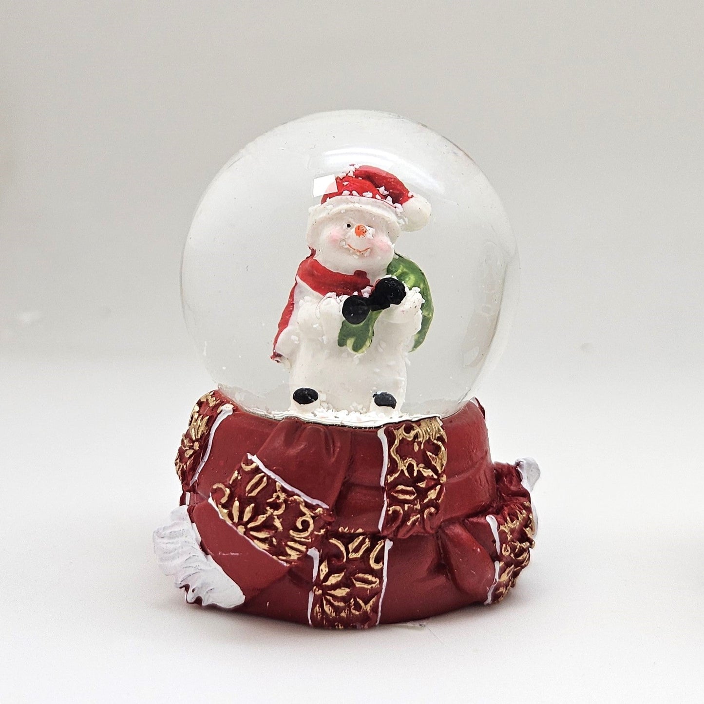 Süße Mini - Schneekugel Schneemann grüner Sack auf Sockel rot gold Winterschal B: 45mm - Schneekugelhaus
