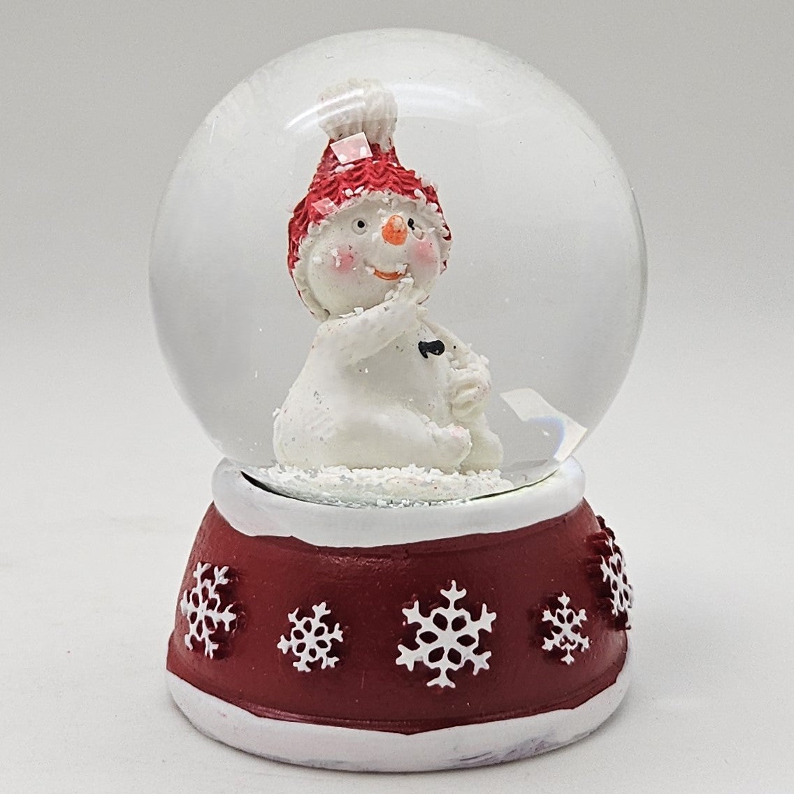 Süße Mini - Schneekugel Schneemann Hand am Mund auf Sockel rot weiße Schneeeflocke B: 45mm - Schneekugelhaus