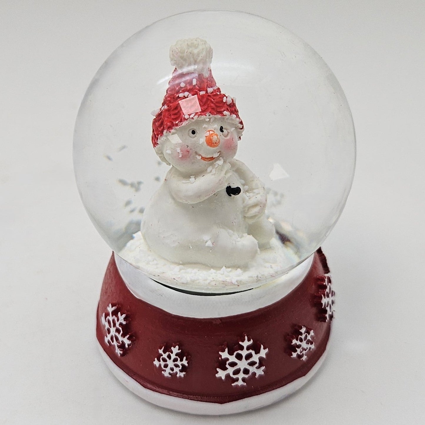 Süße Mini - Schneekugel Schneemann Hand am Mund auf Sockel rot weiße Schneeeflocke B: 45mm - Schneekugelhaus