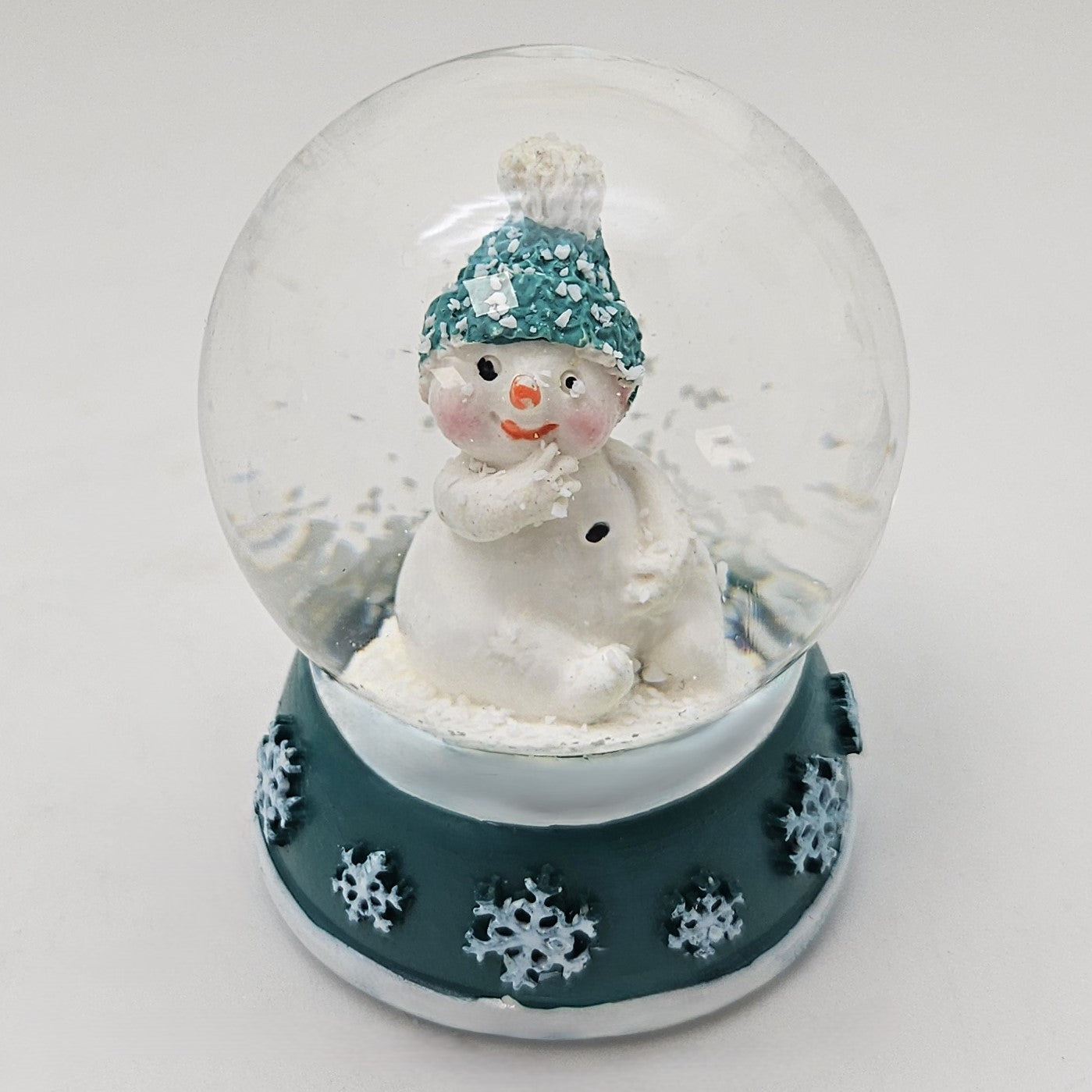 Süße Mini - Schneekugel Schneemann Hand am Mund auf Sockel türkis weiße Schneeeflocke B: 45mm - Schneekugelhaus