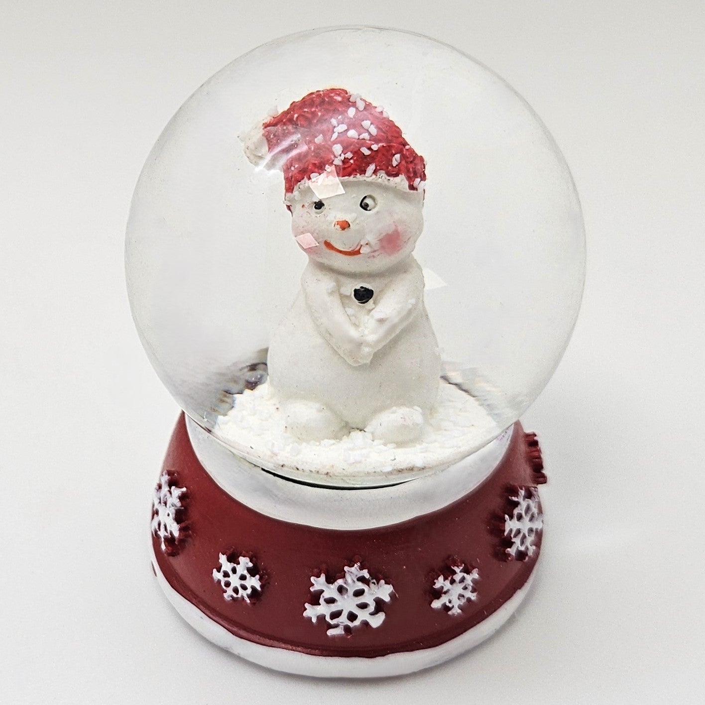 Süße Mini - Schneekugel Schneemann Hände zusammen auf Sockel rot weiße Schneeeflocke B: 45mm - Schneekugelhaus