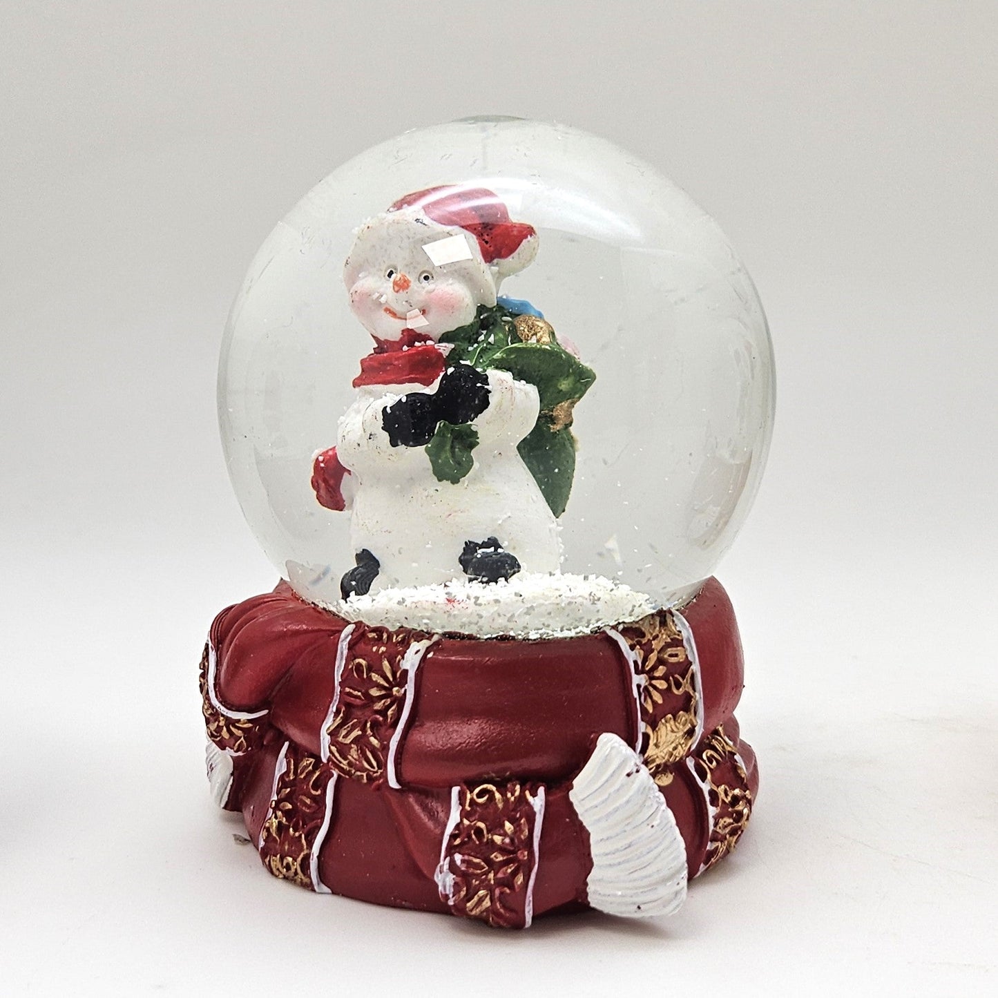 Süße Schneekugel Schneemann grüner Sack auf Sockel rot gold Winterschal B: 65mm - Schneekugelhaus