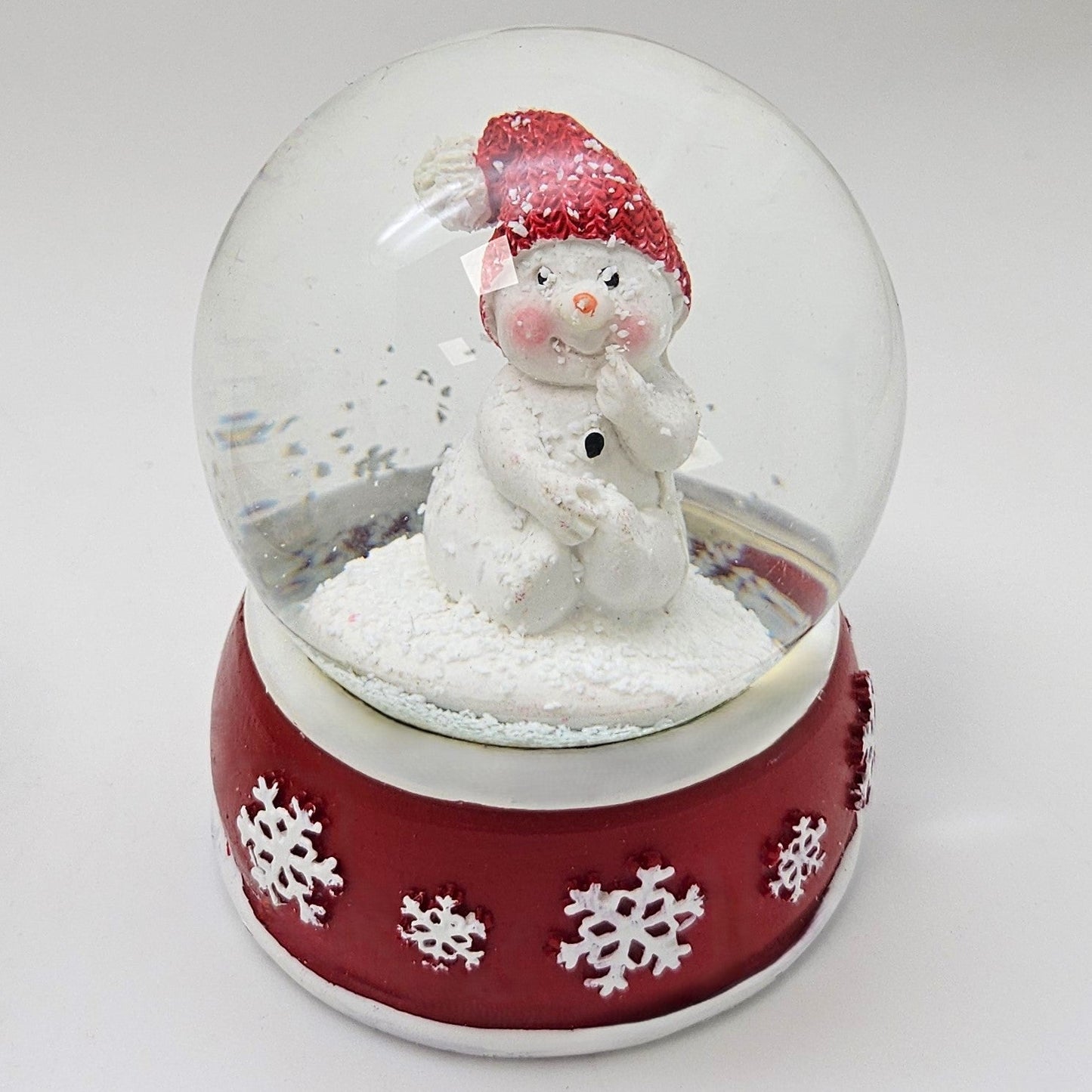 Süße Schneekugel Schneemann Hand am Mund auf Sockel rot weiße Schneeflocke B: 65mm - Schneekugelhaus