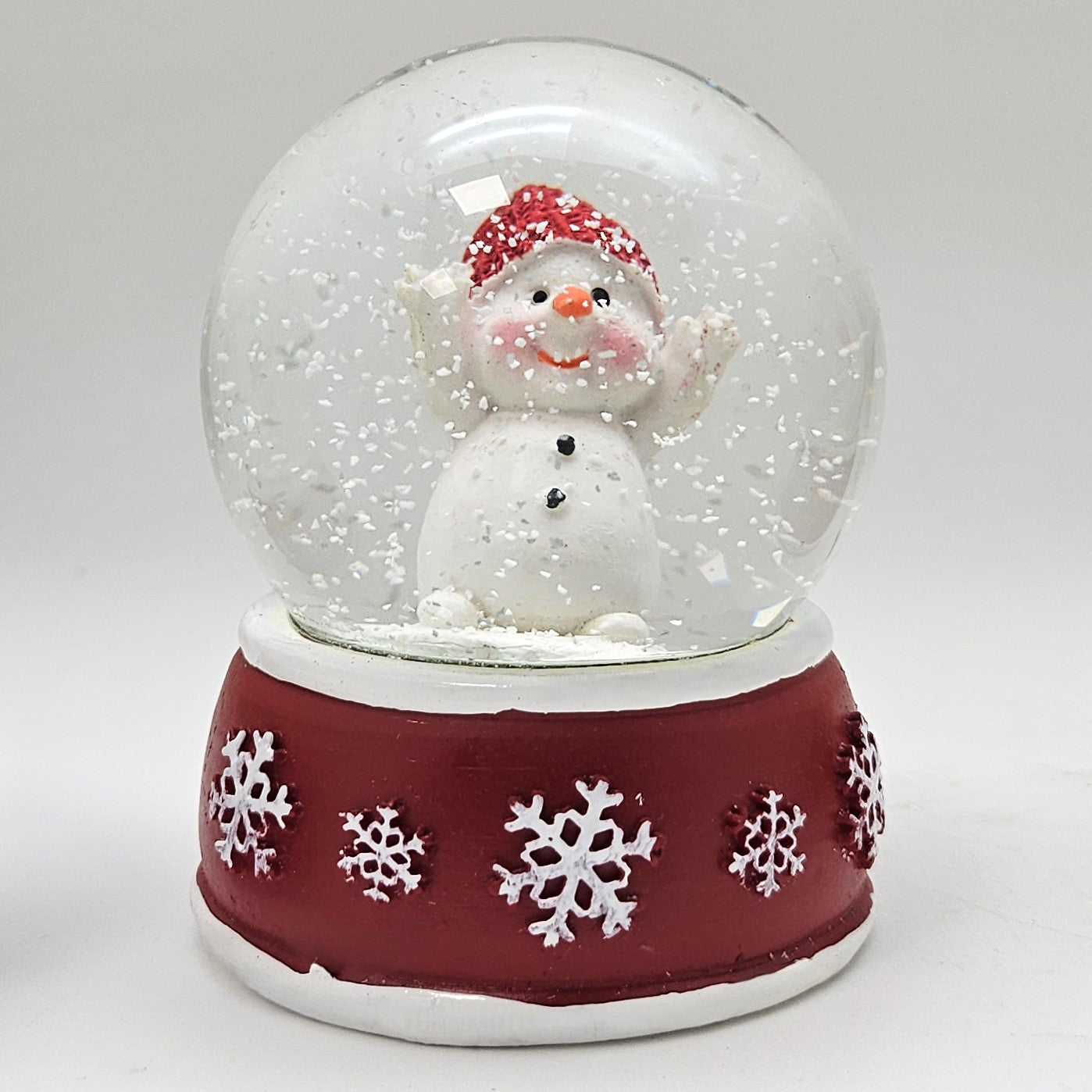 Süße Schneekugel Schneemann Hände hoch auf Sockel rot weiße Schneeflocke B: 65mm - Schneekugelhaus