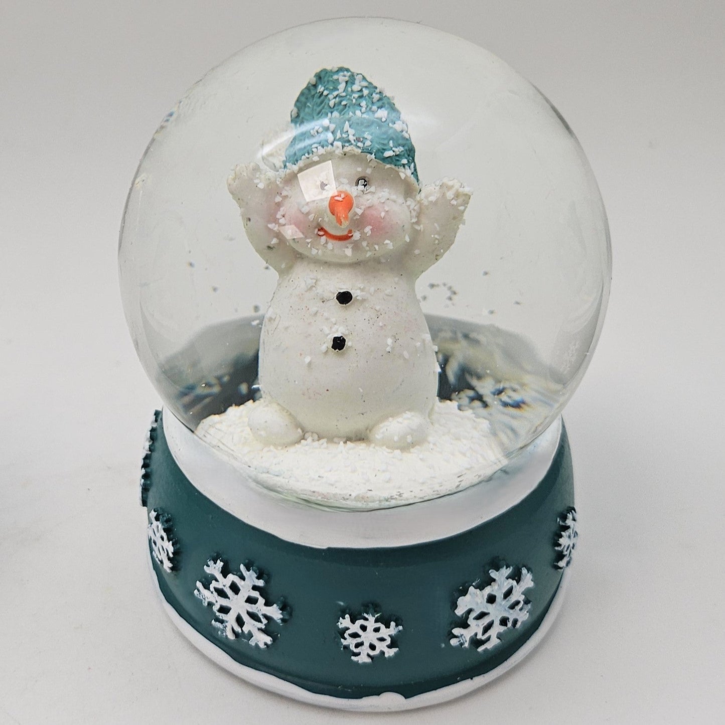 Süße Schneekugel Schneemann Hände hoch auf Sockel türkis weiße Schneeflocke B: 65mm - Schneekugelhaus