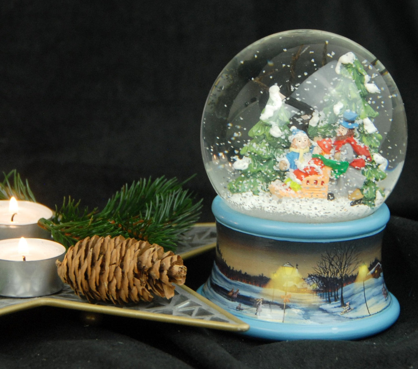 Schneekugel Familie im Winterwald mit Schlitten auf Sockel Winterlandschaft Eisläufer blau mit Spieluhr 10 cm Durchmesser - Schneekugelhaus