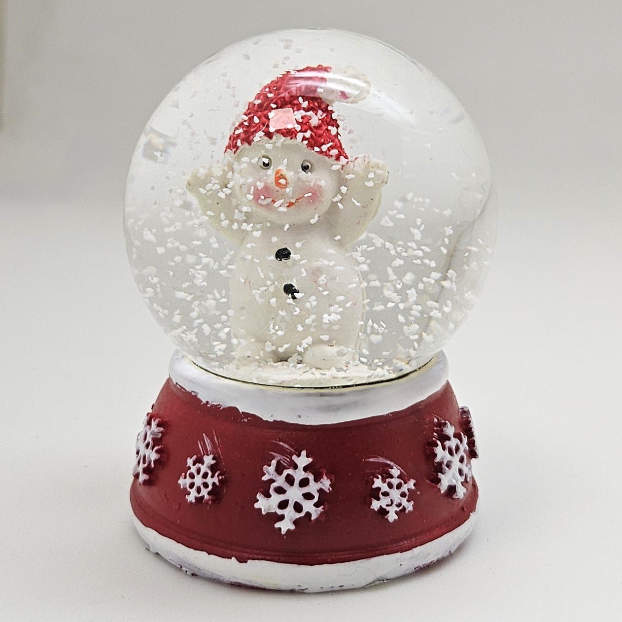 Süße Mini - Schneekugel Schneemann Hände hoch auf Sockel rot weiße Schneeeflocke B: 45mm - Schneekugelhaus