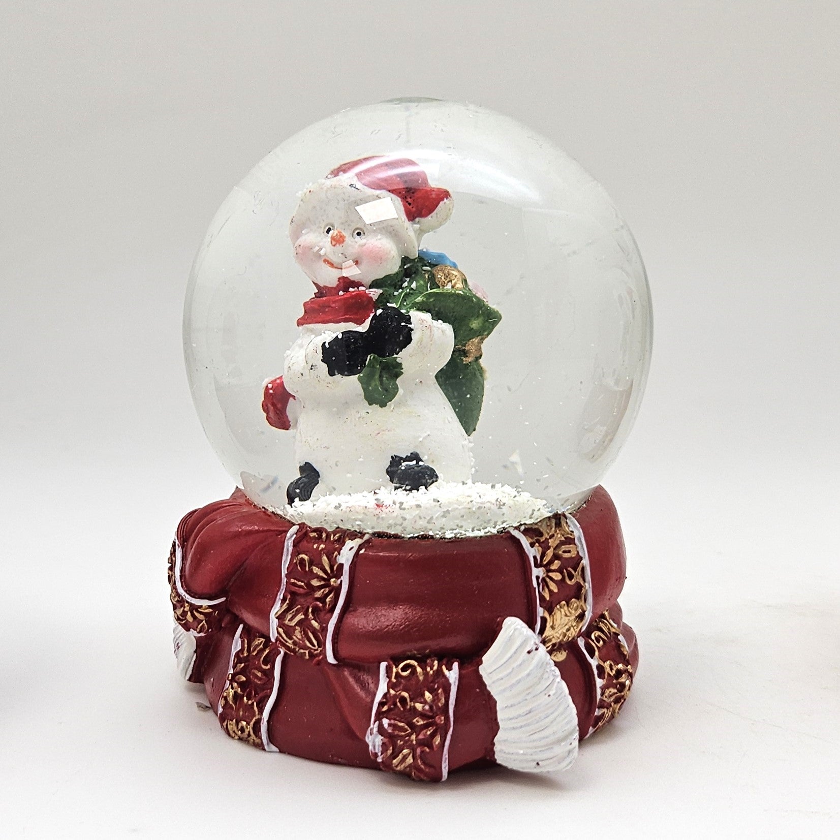 Süße Schneekugel Schneemann grüner Sack auf Sockel rot gold Winterschal B: 65mm - Schneekugelhaus