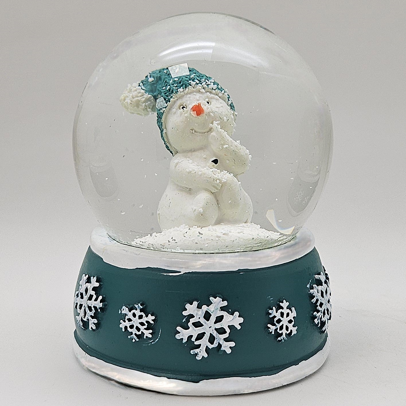 Süße Schneekugel Schneemann Hand am Mund auf Sockel türkis weiße Schneeflocke B: 65mm - Schneekugelhaus