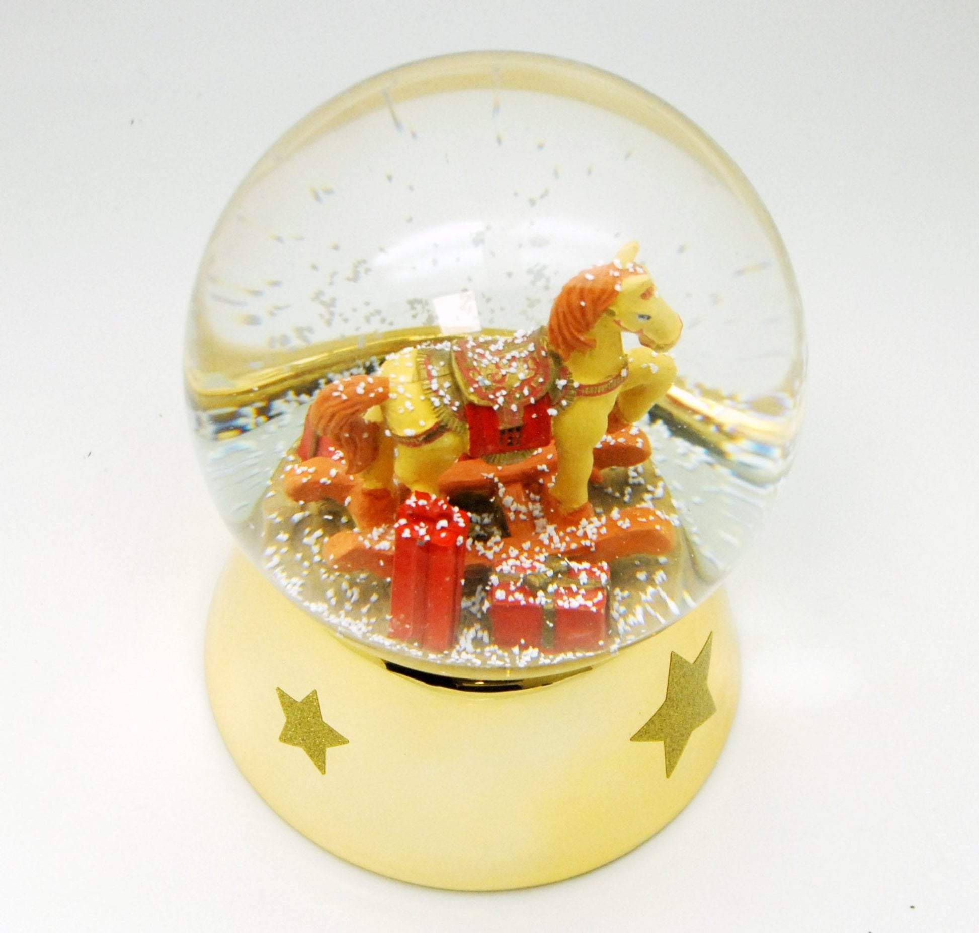 Schneekugel Schaukelpferd rot gold mit Geschenken Sockel gold mit Sternen mit Spieluhr 12 cm Durchmesser - Schneekugelhaus