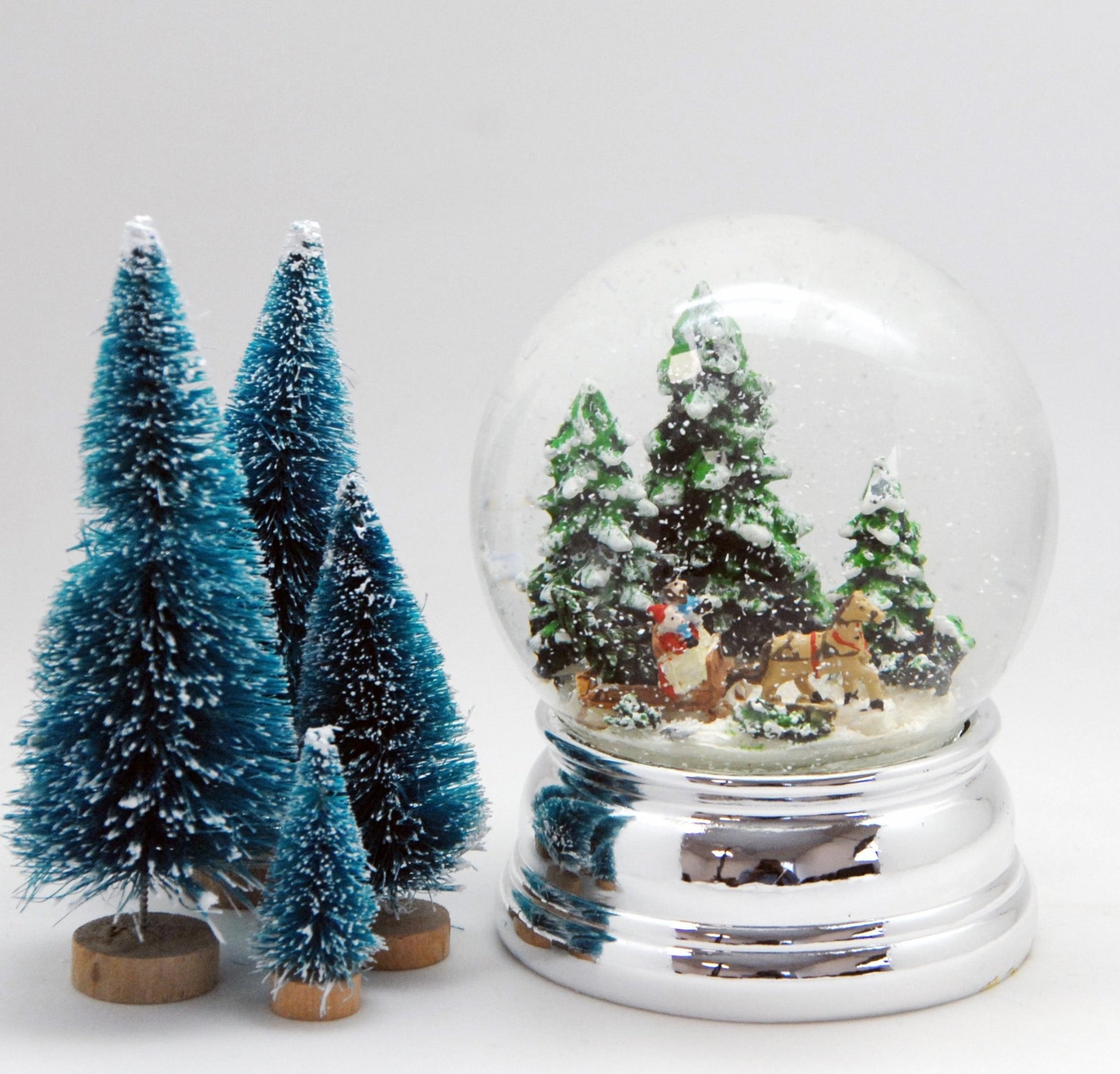 Schneekugel Schlittenfahrt Christbaum holen auf Sockel silber rund geschwungen 10 cm Durchmesser - Schneekugelhaus
