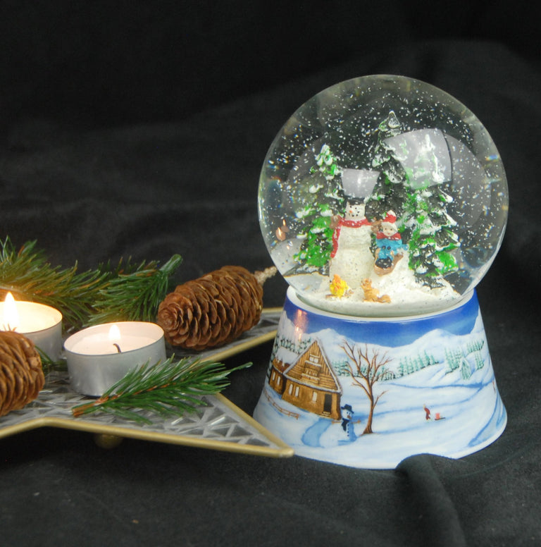 Schneekugel Schneemann bauen mit Lagerfeuer auf Sockel Winterlandschaft mit Spieluhr 10 cm Durchmesser - Schneekugelhaus